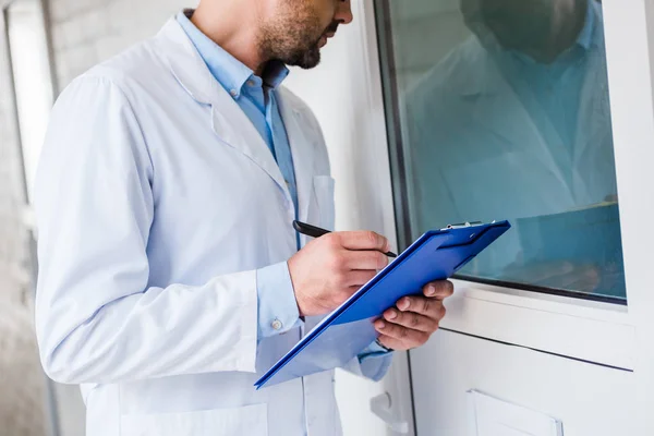 Image recadrée du vétérinaire avec des salles de contrôle presse-papiers à la clinique vétérinaire — Photo de stock