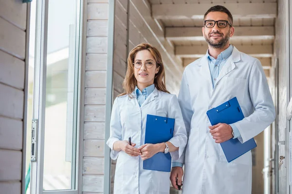 Two veterinarians in white coats walking with clipboards in veterinary clinic — Stock Photo