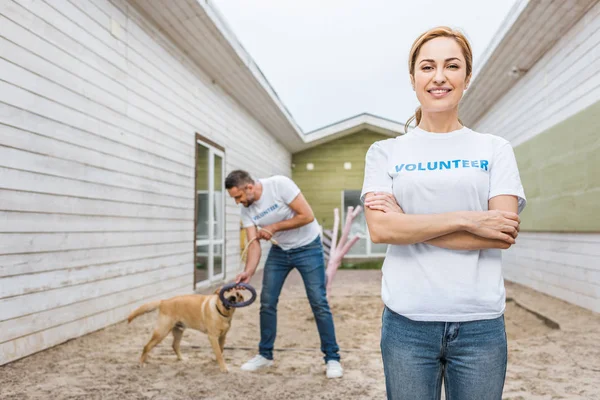 Bénévole des animaux abri jouer avec labrador chien, femme regardant caméra — Photo de stock