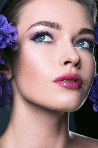 Nahaufnahme Porträt einer schönen jungen Frau mit modischem Make-up und Eustoma-Blumen — Stockfoto