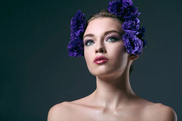 Ritratto ravvicinato di bella giovane donna con fiori di eustoma sulla testa guardando lontano isolato sul grigio — Foto stock