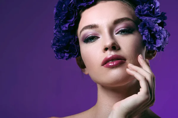 Ritratto ravvicinato di giovane donna seducente con fiori di eustoma corona sulla testa guardando la fotocamera isolata su viola — Foto stock