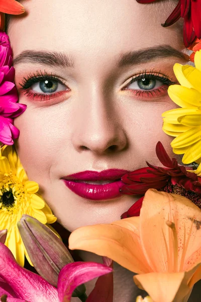 Portrait en gros plan de belle jeune femme entourée de diverses fleurs regardant la caméra — Photo de stock