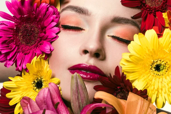 Close-up portrait of beautiful young woman with closed eyes surrounded with various flowers — Stock Photo