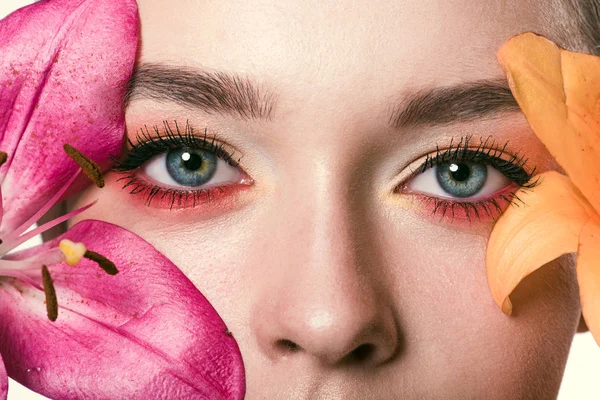 Vista parziale ritratto di bella giovane donna con fiori di lilium guardando la macchina fotografica — Foto stock