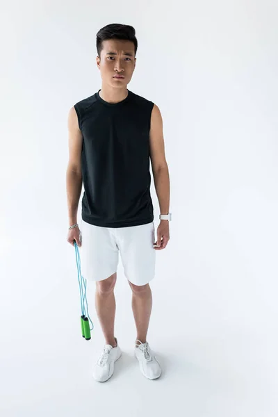 Sério jovem asiático desportista de pé com salto corda no fundo cinza — Fotografia de Stock