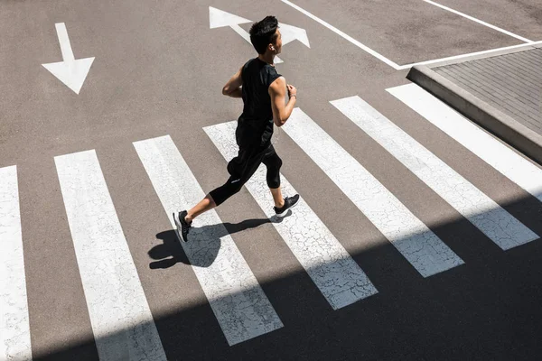 High angle view of young asian sportsman in earphones running at city street — Stock Photo