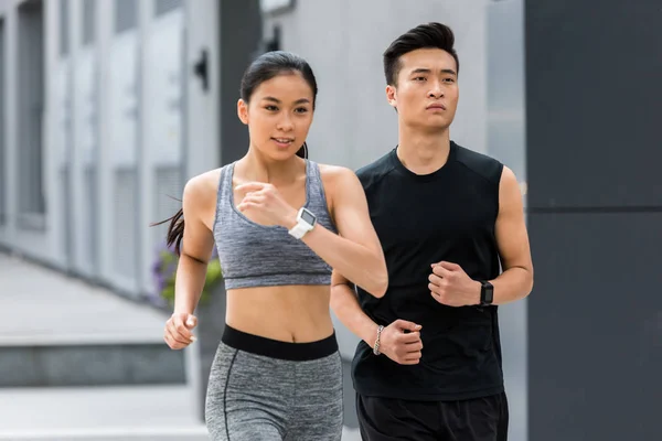 Asiático sportsman y sportswoman corriendo en ciudad calle - foto de stock