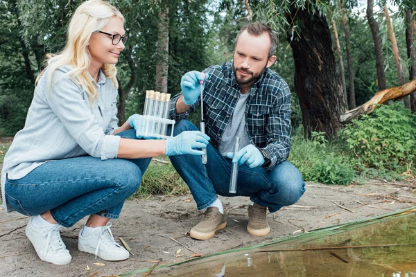 Wissenschaftlerinnen und Wissenschaftler testen Wasserprobe in Testkolben im Wald — Stockfoto