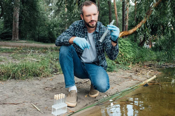 Wissenschaftler in Latexhandschuhen entnimmt Wasserprobe in Reagenzglas im Freien — Stockfoto