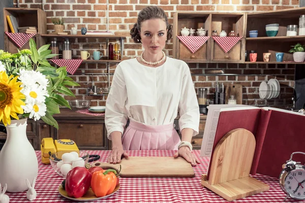 Sérieux adulte ménagère en vêtements vintage regardant caméra à la cuisine — Photo de stock