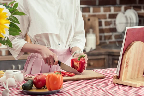 Plan recadré de femme au foyer coupant poivron à la cuisine — Photo de stock