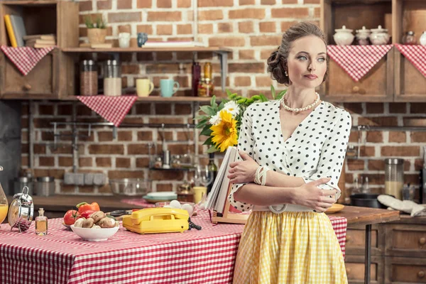 Ama de casa adulta seria en ropa vintage mirando hacia la cocina - foto de stock