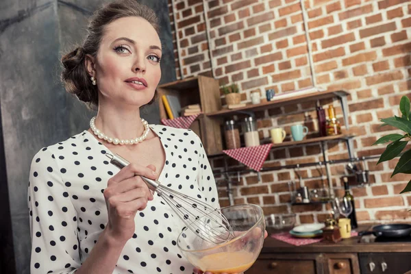 Beautiful adult housewife whisking eggs for omelette at kitchen — Stock Photo