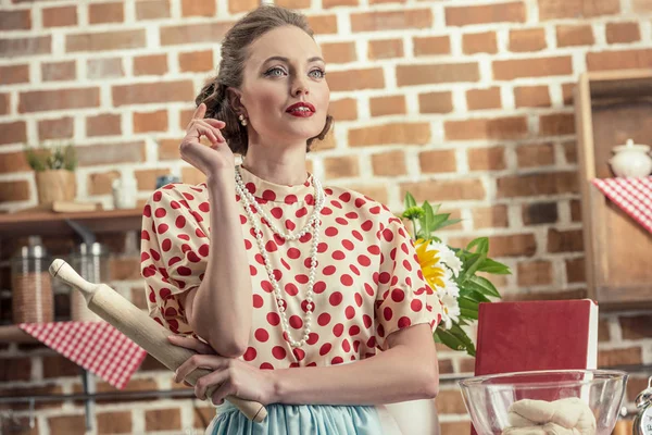 Nachdenkliche erwachsene Hausfrau mit Nudelholz, die in die Küche schaut — Stockfoto
