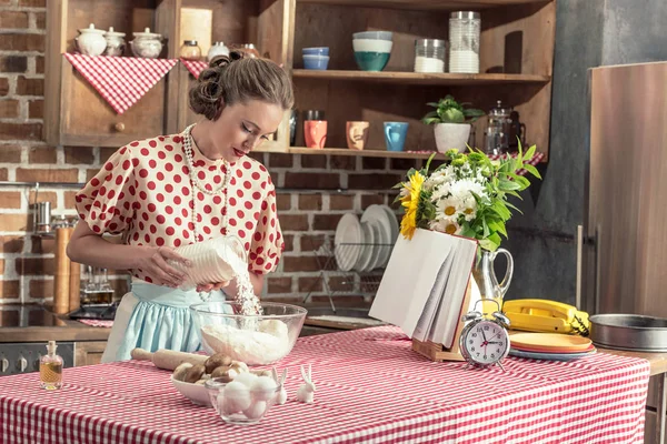 Attraktive erwachsene Hausfrau gießt Mehl in Schüssel für Teig in der Küche — Stockfoto