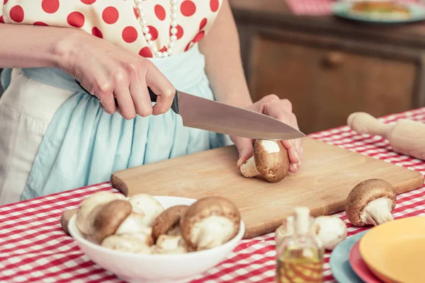 Tiro cortado de dona de casa em bolinhas ponto camisa cortando cogumelos na cozinha — Fotografia de Stock