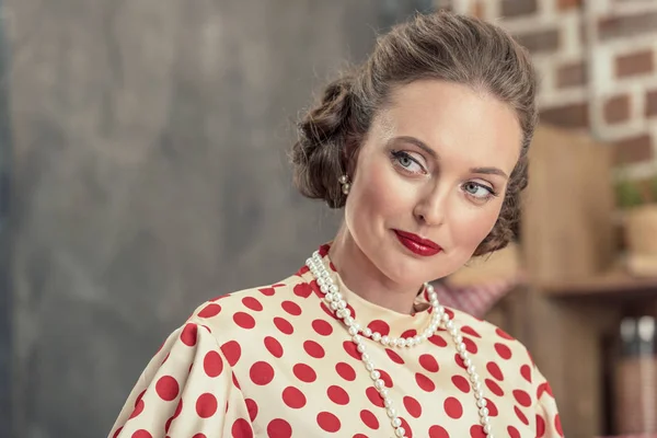 Close-up portrait of beautiful adult woman in vintage polka dot shirt and pearl necklace looking away — Stock Photo