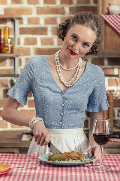 Heureuse femme au foyer adulte coupe gâteau aux champignons frais et regardant la caméra à la cuisine — Photo de stock