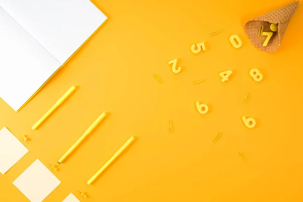 Flat lay with blank notebook with various studying supplies and waffle cone on yellow — Stock Photo