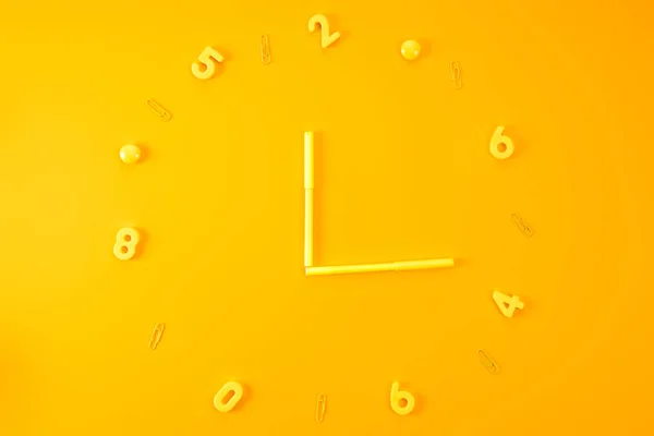 Top view of watch made of markers, plastic digits and paper clips on yellow — Stock Photo