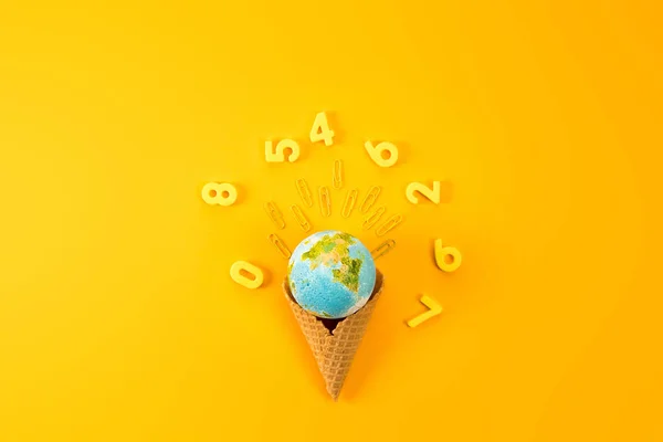 Vista superior del globo terráqueo en cono de gofre rodeado de dígitos en amarillo - foto de stock