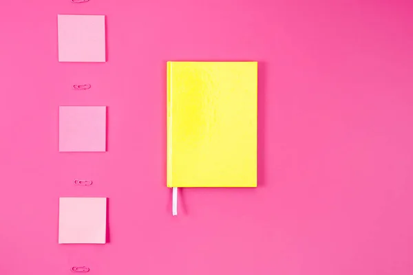 Flat lay com caderno amarelo com adesivos e clipes de papel em rosa — Fotografia de Stock