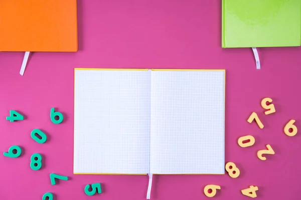 Vista superior del cuaderno en blanco abierto y números de educación matemática en rosa - foto de stock