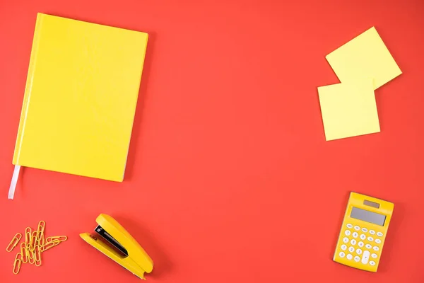 Top view of various yellow office appliances on red — Stock Photo