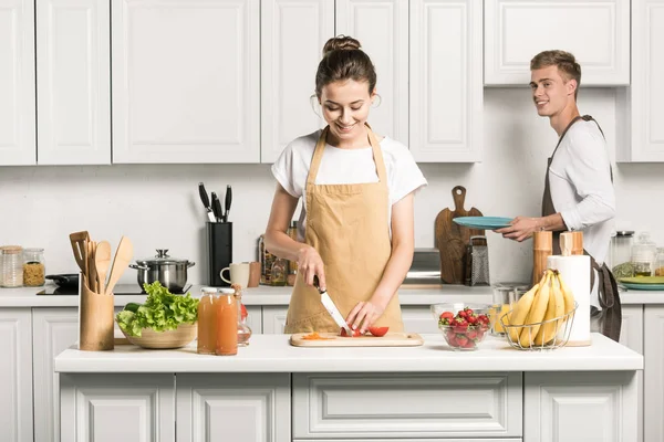 Copine cuisine la salade et couper les tomates dans la cuisine — Photo de stock