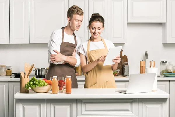 Jovem casal olhando para tablet na cozinha — Fotografia de Stock