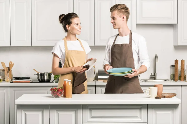 Jovem casal secando pratos na cozinha — Fotografia de Stock