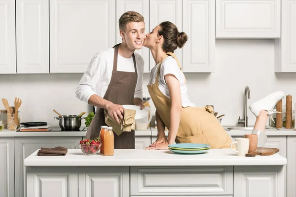 Namorada beijando namorado para secar pratos na cozinha — Fotografia de Stock