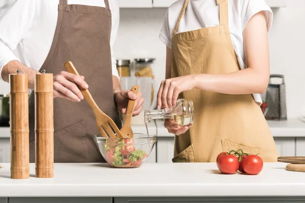 Cropped image of young couple preparing salad in kitchen — Stock Photo