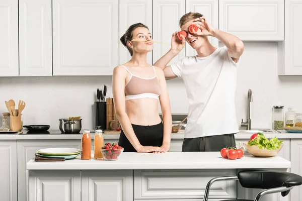 Jeune couple s'amuser tout en cuisinant des pâtes dans la cuisine — Photo de stock