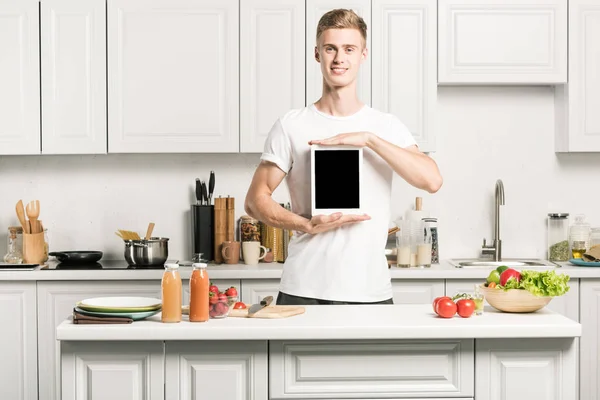 Jovem bonito segurando tablet com tela em branco na cozinha — Fotografia de Stock