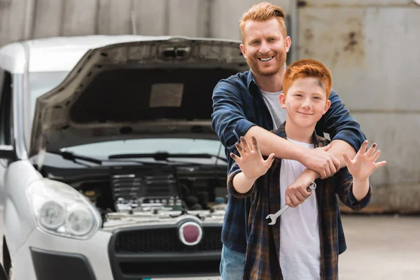 Father hugging son after repairing car and he waving hand — Stock Photo