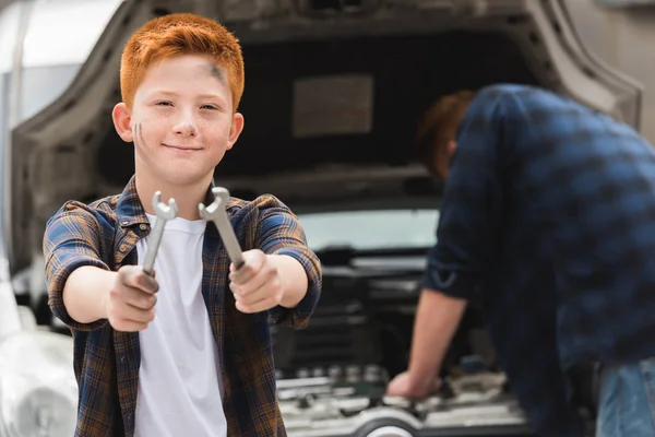 Padre reparación de coche con capucha abierta, hijo mostrando herramientas - foto de stock