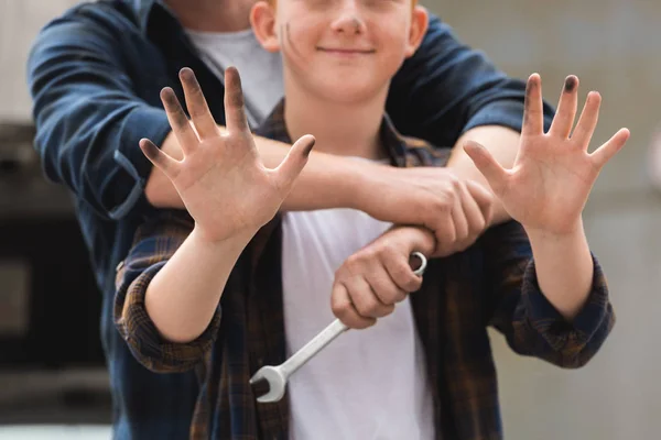 Cropped image of father hugging son after repairing car and he showing dirty hands — Stock Photo