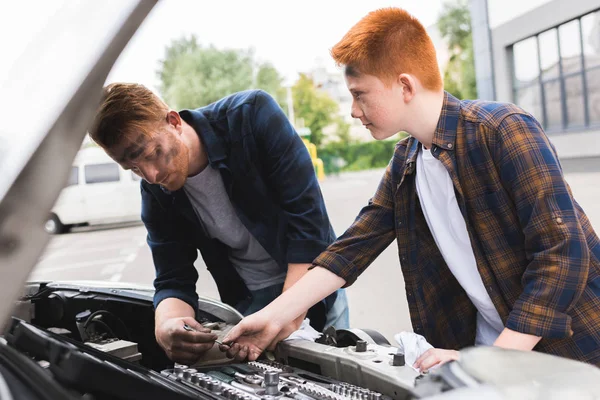 Son giving tool for repairing car to father — Stock Photo