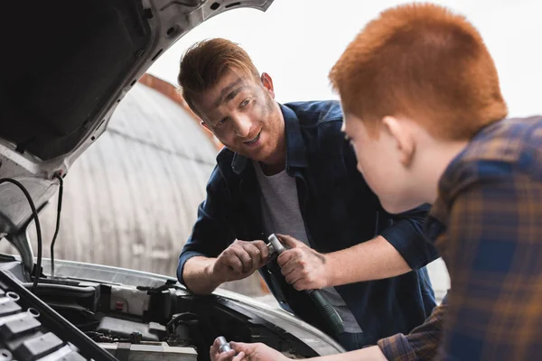 Vater und Sohn reparieren Auto mit offener Motorhaube und schauen einander an — Stockfoto