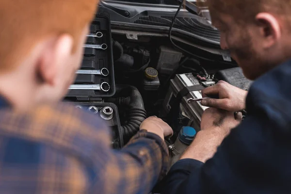 Cropped image of father and son repairing car with open hood — Stock Photo