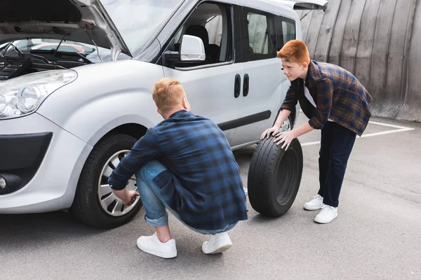 Father and son changing tire in car with wheel wrench on weekend — Stock Photo