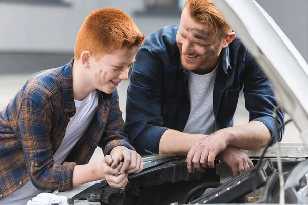 Happy father and son repairing car with open hood — Stock Photo