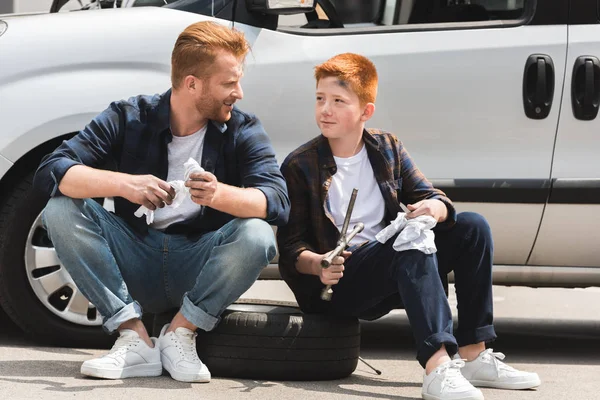 Father and son holding tools for repairing car and looking at each other — Stock Photo