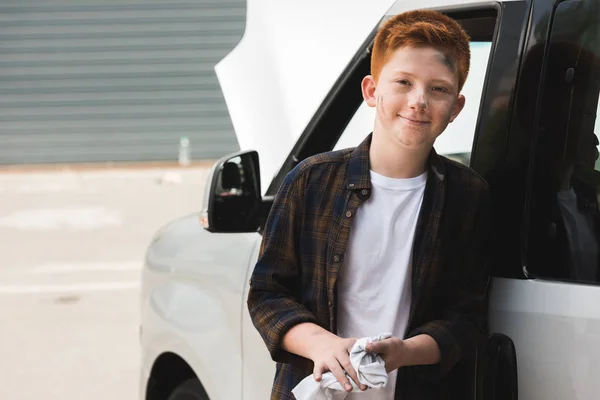 Cheerful red hair preteen boy looking at camera after repairing car — Stock Photo