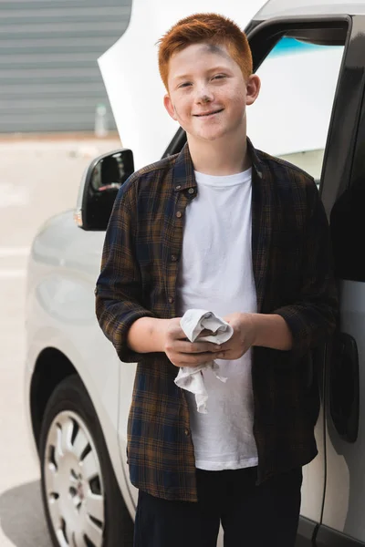 Dirty red hair preteen boy cleaning hands after repairing car — Stock Photo