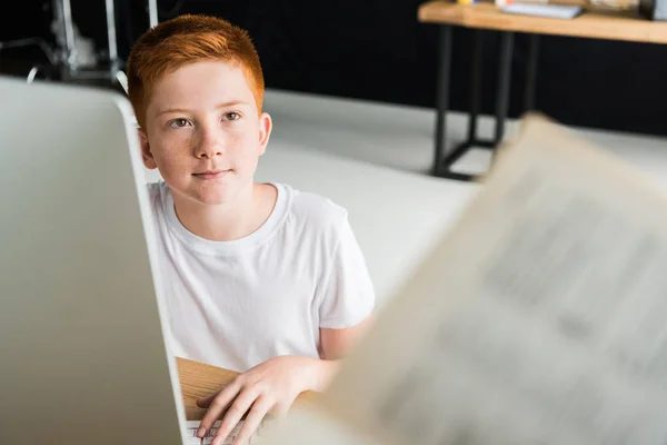 Junge sitzt am Tisch mit Computer und schaut zu Hause weg — Stockfoto