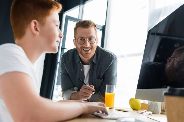 Smiling father looking at son using computer at home — Stock Photo