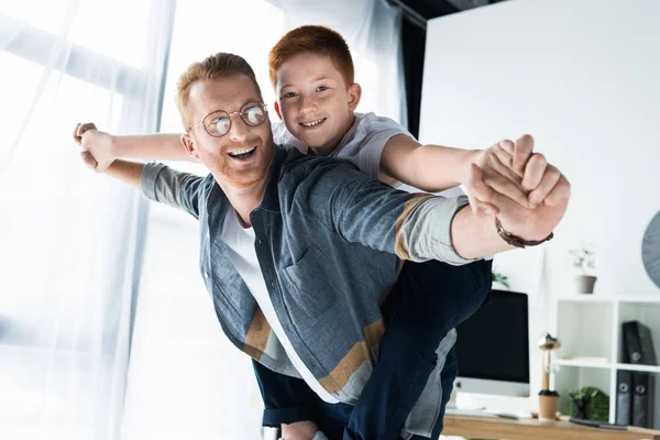 Lächelnder Vater gibt Sohn zu Hause Huckepack — Stockfoto